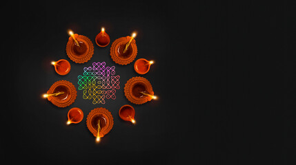 Decorated natural lit clay oil lamp placed on dark black background with copy space, Diwali...