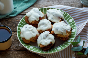 Cinnamon rolls with cream, round yeast buns. Side view, wooden background.