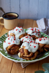 Cinnamon rolls with cream and freeze-dried strawberries, round yeast rolls. Side view, wooden background.