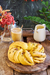 Pumpkin bun with pumpkin seeds and walnuts. Pumpkin latte, walnuts, rowan branch, wooden background, side view.