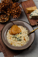 Gorgonzola and pear risotto with walnuts on grey table. Ingredients on background. Copy space.