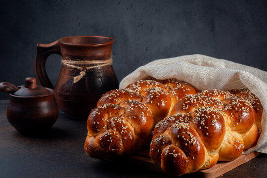 Homemade Challah bread with white cover. Main ingredients are eggs, white flour, water, sugar, salt and yeast. Decorated with sesame and poppy seeds. Dark background.