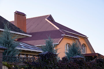 The roof of the house is made of red metal tiles, a beautiful large chimney.
