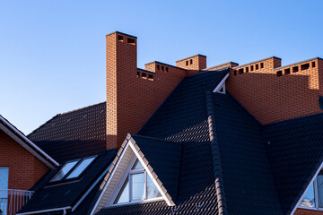 Large roof with brown metal tiles and chimneys.