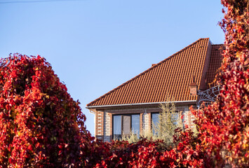 The roof is made of red metal tiles in the fall.