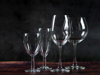 Wine glasses and champagne glasses placed on a table against a black background.