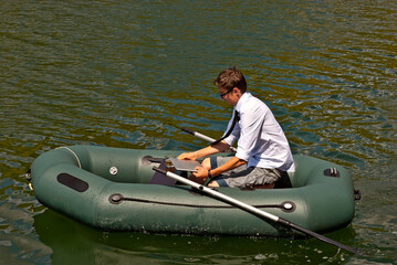 A man in a white shirt on an inflatable boat. Businessman with laptop resting on the lake. The concept of remote work, leisure and freelance.