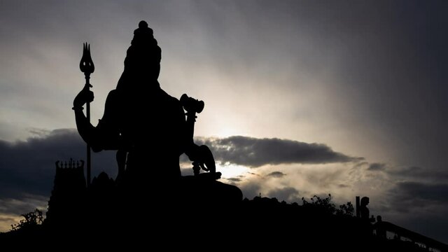 Statue of meditating Hindu God Shiva, Time Lapse at Sunrise with Fast Clouds