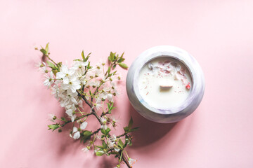 Ecological and vegan handmade candle with dry flowers in a glass made of concrete on a pink background. Soy or coconut candle with a wooden wick.