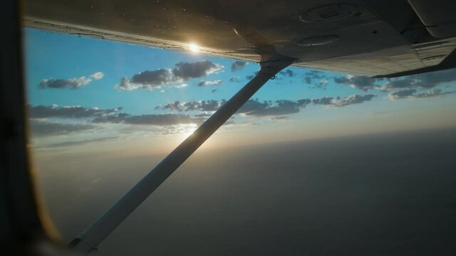 Man flying a small Cessna plane during the sunrise.