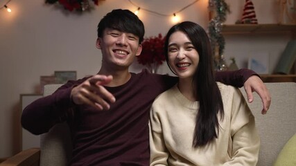 Happy asian young couple waving hands face camera making online video call enjoying family virtual meeting sitting on couch at home. front view cheerful man hug girlfriend and talking on internet - Powered by Adobe
