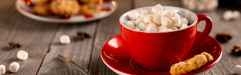 Hot chocolate with marshmallow in red cup on wooden table