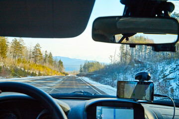 Siberia, Russia - November 28, 2020: View from of car interior from side of driver to the road and nature landscape through the windshield