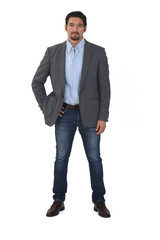front view of a man with blazer and jeans with hands on hip on white background