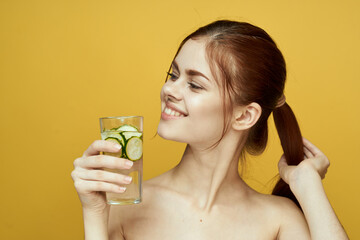 woman with cucumber drink vitamins body care yellow background