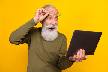 Photo of impressed aged white beard man look in laptop wear eyewear green sweater isolated on...