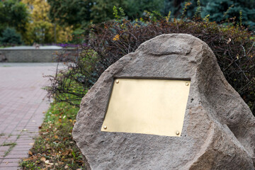 Blank plaque on the stone. Bronze memorial plaque in the park. Empty sign board on the wall.