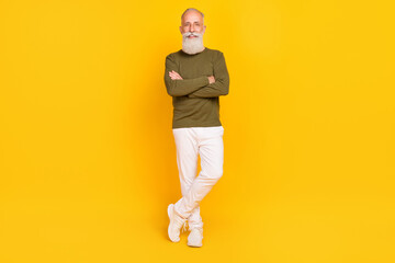 Full length body size view of attractive cheery grey-haired man posing folded arms isolated over bright yellow color background