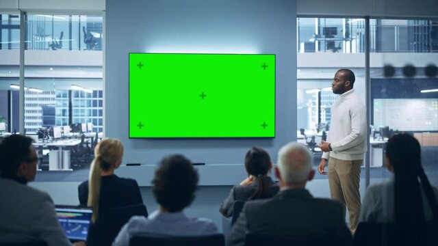 Modern Product Presentation Event: Black Businessman Speaks, Uses Green Chroma Key Screen Wall TV. Press Conference for Group of Diverse Multi-Ethnic Investors, Digital Entrepreneurs, Businesspeople