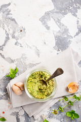 Homemade parsley pesto sauce and ingredients on dark cement background. Close up wiev of basil pesto in glass jar with ingredients.