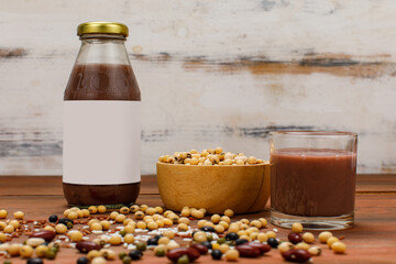 Healthy vegetarian beverage glass bottle and cup on kitchen table with ingredient bowl of soybean grain and brown rice