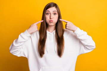 Portrait of attractive funny cheerful girl holding air in cheeks pressing isolated over bright yellow color background
