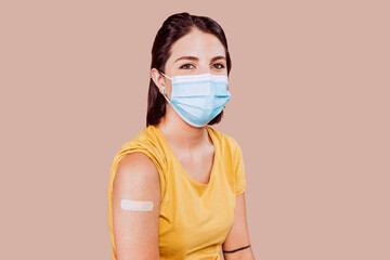Portrait of a young female wearing protective mask after receiving a vaccine. Woman showing her bandaged arm after receiving vaccination. Copy space.