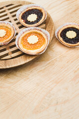 Obraz na płótnie Canvas apricot and cherry jam shortcrust pastry in a paper backing cup on a wooden chopping board background