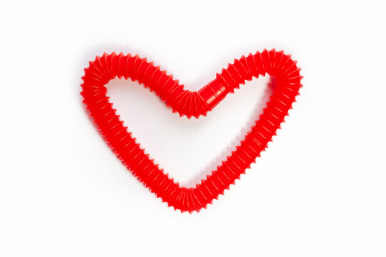 pop tube trending toy of 2021. anti-stress sensory figet plastic toy. multicolored bright tubes isolated on white background in the shape of a heart. copy space. top view.