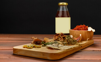 Healthy dry herb and glass bottle of tasty organic mixed drink served on wooden tray for recipe of natural detox medicine and nourishment supplementary food