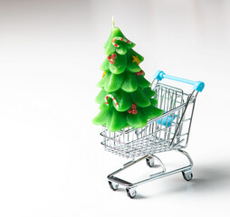 Supermarket basket with green candle Christmas tree on white background.