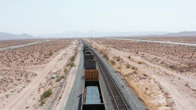 Aerial Drone Views Flying Over Train in  Mojave Desert Dry Lands. Freight train stopped in the desert. Aerial drone shot of cargo train. Aerial view of train tracks in the desert. 