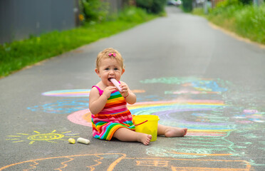 Fototapeta premium The child draws with chalk on the asphalt. Selective focus.