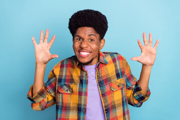 Photo of impressed funny dark skin man wear plaid shirt smiling rising arms isolated blue color background