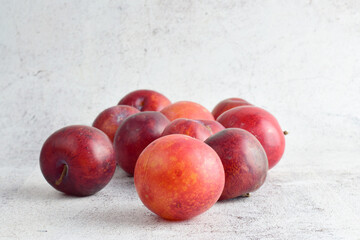 Close up, red plums scattered on gray stone background. Copy space.