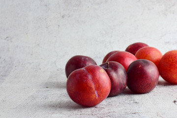 Fruits, red plums scattered on gray stone background.