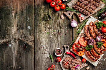 Various kinds of grilled gourmet meats on a rustic wooden table. Barbecue menu. banner, menu, recipe place for text, top view