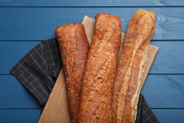 Tasty buckwheat baguettes on blue wooden table, flat lay
