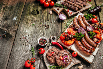 Grilled meat assortment of tasty bbq snacks on wooden background. Barbecue menu. banner, menu, recipe place for text, top view - obrazy, fototapety, plakaty