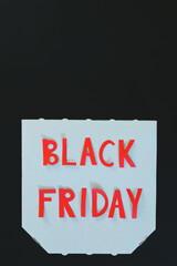 Inscription "black friday" on a white cardboard pizza box on black background. Copy space, top view, flat lay. Creative holiday flyer. Sale. 