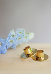 Small metal candlestick with flowers on wooden table.