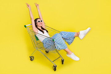 Portrait of attractive cheerful girl sitting in cart having fun showing v-sign isolated over bright...