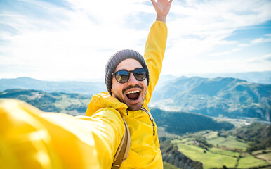 Young hiker man taking selfie portrait on the top of mountain - Happy guy smiling at camera - Hiking, sport, travel and technology concept - Bright filter - obrazy, fototapety, plakaty