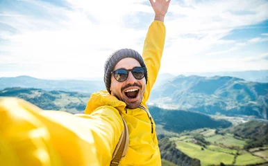 Foto op Canvas Young hiker man taking selfie portrait on the top of mountain - Happy guy smiling at camera - Hiking, sport, travel and technology concept - Bright filter © Davide Angelini