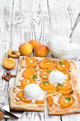 Homemade apricot pie served with ice-cream on white wooden table