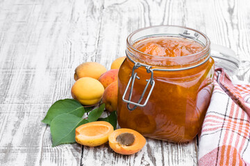 Apricot jam in a glass jar on white wooden table