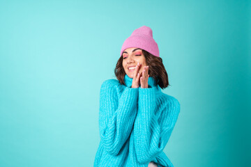 Cozy portrait of a young woman in a knitted blue sweater and a pink hat with bright makeup
