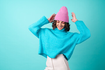 Cozy portrait of a young woman in a knitted blue sweater and a pink hat with bright makeup