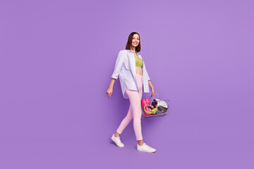 Fototapeta na wymiar Full length profile photo of funky brunette millennial lady go wear top shirt jeans sneakers isolated on violet background