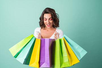 Fototapeta na wymiar Young woman in a white evening dress on a light green background with bright pink makeup holds shopping bags